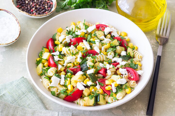 Pasta salad with tomatoes, zucchini, corn and feta cheese. Healthy eating. Vegetarian food.