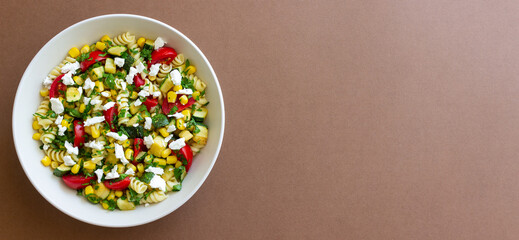 Pasta salad with tomatoes, zucchini, corn and feta cheese. Healthy eating. Vegetarian food.