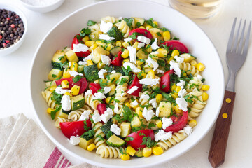 Pasta salad with tomatoes, zucchini, corn and feta cheese. Healthy eating. Vegetarian food.