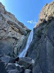 Scenic view of Upper Yosemite Falls cascading down the granite cliffs with trees in Yosemite National Park, California, USA.