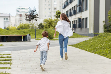 Mother and son running through modern residential park