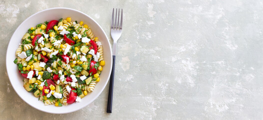 Pasta salad with tomatoes, zucchini, corn and feta cheese. Healthy eating. Vegetarian food.