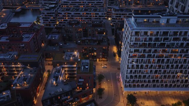 Aerial drone view of Orestad's residential district with illuminated modern apartment blocks at night in Copenhagen, Denmark