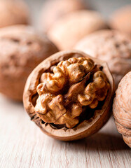 Fototapeta premium Walnuts with shells and a focus on a single opened nut on a wooden surface, showcasing their rich texture and natural color