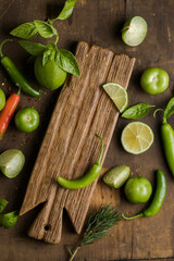 Tomatillo, chili, tomato  lime and basil on wooden background with copy space