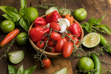 Bowl of fresh tomatoes with garlic. Tomatillo, chili, tomato  lime and basil on wooden background with copy space