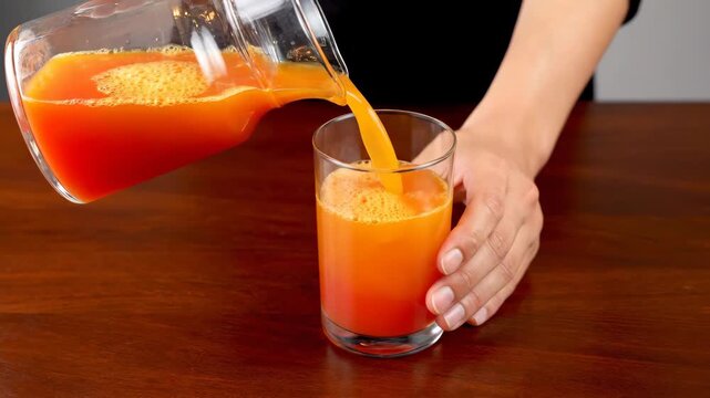 Pouring Fresh Orange Juice Into Glass Over Egg Yolk on Kitchen Table