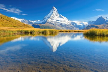 Naklejka premium Alpine lake mirroring a snow-capped peak under a clear blue sky