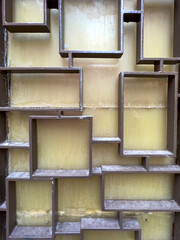 A close-up of a decorative metal grille featuring an abstract geometric pattern of interlocking squares and rectangles. 