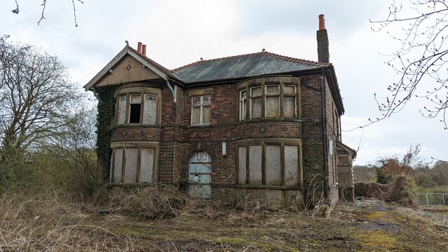 Abandoned ghost story hoax home. Derelict empty 'Haunted Murder House' Heskin, Lancashire. Brick building boarded up bay windows, desolate overgrown garden. Decaying creepy neglected property exterior