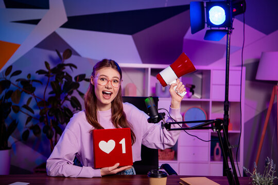 Popular female blogger with megaphone hosting a podcast in a vibrant studio, showcasing social media engagement and interaction - Powered by Adobe