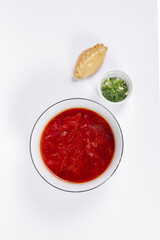 An appetizing portion of rich red borscht garnished with fresh herbs and spicy pies.