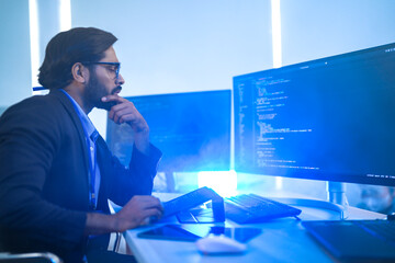 A back-end developer working on complex code in a futuristic command center. A lone programmer focused on a multi-monitor setup in a high-tech, atmospheric data hub.