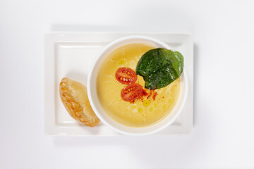 top view of a healthy pumpkin soup in a bowl with a spoon on a white plate with a pie