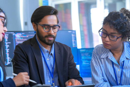 A team of software engineers celebrates a successful code deployment. They review the final user interface (UI) and user experience (UX) on a tablet after a collaborative debugging session.