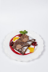 Chocolate pancakes with fruits and chocolate on white plate