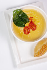 top view of a healthy pumpkin soup in a bowl with a spoon on a white plate with a pie