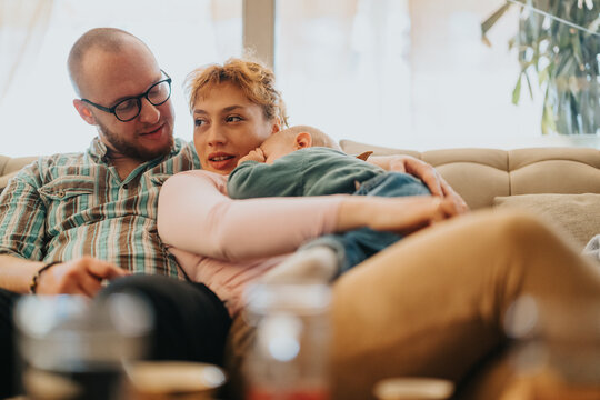 A loving family sits together on a comfortable couch, showcasing warmth, care, and relaxation. The environment reflects a peaceful and joyous moment in their home on a sunny day.