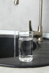 Beaker with clean water near sink on counter in kitchen, closeup