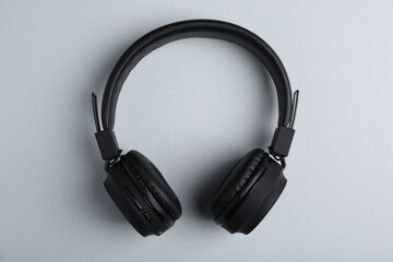 Pair of stylish black headphones on light grey background, top view