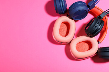 Different stylish headphones on pink background, flat lay. Space for text