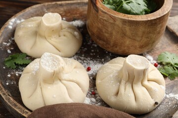 Uncooked khinkalis (dumplings) with peppercorns and parsley on table, closeup