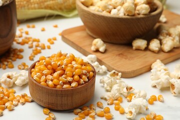 Corn kernels and tasty popcorn on white table, closeup