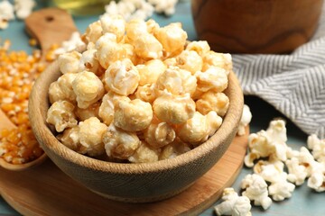 Tasty popcorn and corn kernels on blue wooden table, closeup
