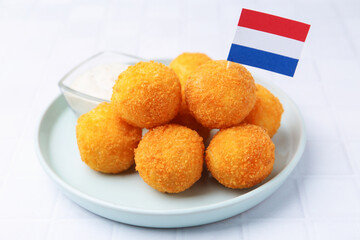 Delicious fried croquette balls and flag of Netherlands on light tiled table, closeup