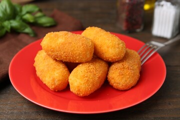 Delicious fried croquettes on wooden table, closeup