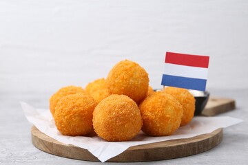 Delicious fried croquette balls and flag of Netherlands on gray table, closeup