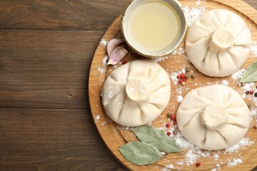 Uncooked khinkalis (dumplings) with peppercorns, flour and bay leaves on wooden table, top view. Space for text