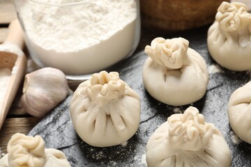 Uncooked khinkalis (dumplings), flour and garlic on table, closeup