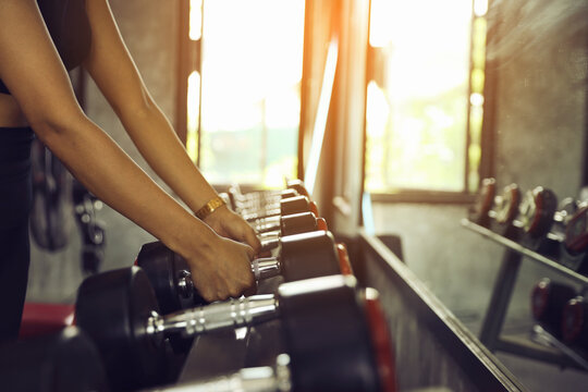 Woman Reaching for Dumbbell in a Gym. Fitness: Getting Ready for a Workout.