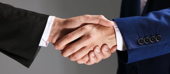Obraz premium Business partners shaking hands on grey background, closeup