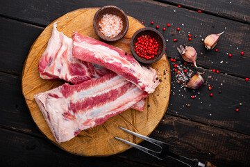 Raw pork ribs chopped on a cutting wooden board, a black wooden background top view, raw pork meat