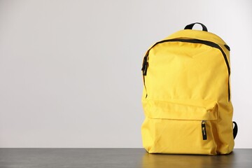 Yellow backpack on table against light background. Space for text