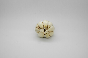 A single garlic clove positioned on a clean white background, perfectly capturing its intricate textures and unique shape