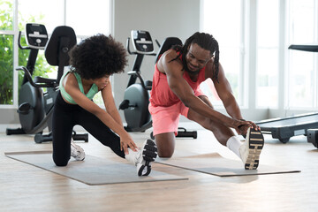 African American young girl and coach or personal trainer teaching by stretching or warm up in fitness gym. Healthy lifestyle concept