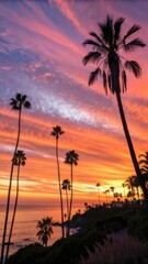 Fototapeta premium Vibrant tropical sunset sky over ocean with silhouetted palm trees and wispy clouds