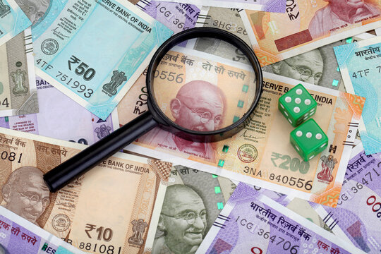 Magnifying glass and green dice on Indian currency notes 