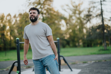 A man grimaces in discomfort as he experiences back pain while exercising outdoors in a park. The image captures a moment of struggle and illustrates the challenges of physical exertion.