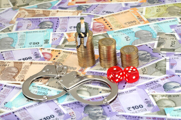 Handcuffs,dice and stack of coins on Indian currency notes