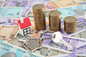 Model house,house-key and stack of coins on Indian currency notes 