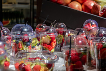 Colorful fruit cups filled with fresh strawberries, blueberries, kiwi, and raspberries displayed in clear containers, showcasing healthy snacks with vibrant colors and textures
