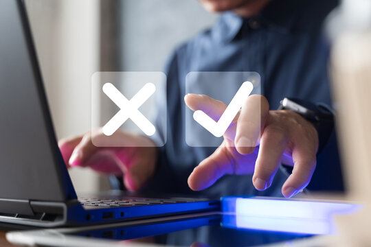 Businessman using laptop with digital check mark and cross icons, decision making and online approval