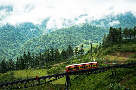 Red funicular train ascending mountain valley in Sapa, Vietnam