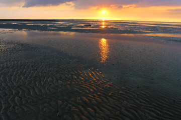 Reflections of the sunset on the water surface in the mudflats