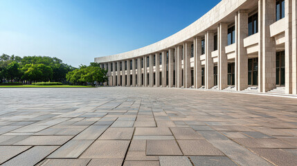 Obraz premium Modern architectural structure featuring curved facade, large columns, and spacious stone plaza clear blue sky. scene conveys sense of openness