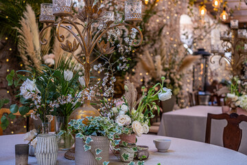 Elegant table setting adorned with lush flowers and greenery, featuring a vintage candelabra, creating a cozy and inviting atmosphere for a modern wedding celebration with decorative elements